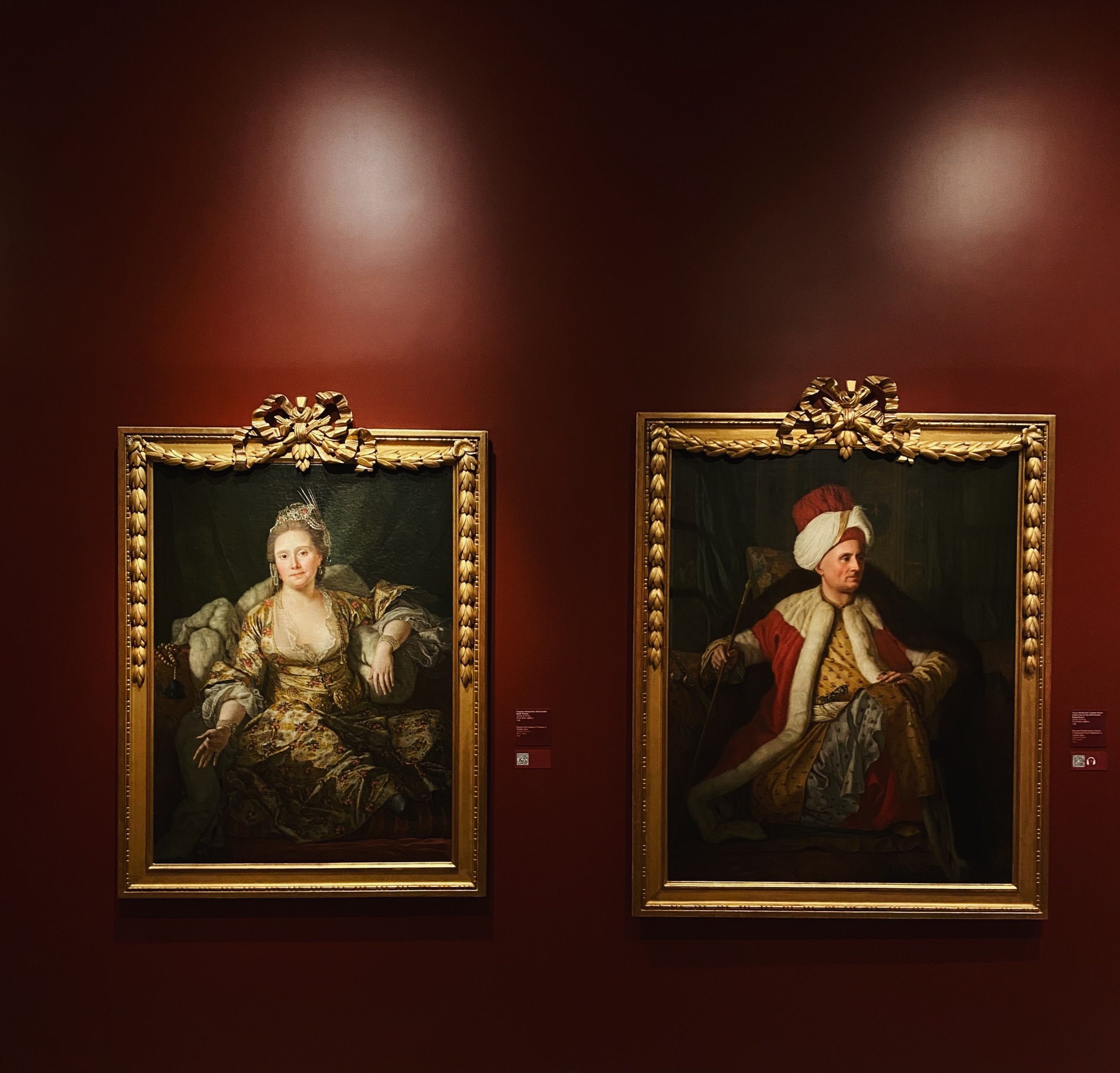 Deux portraits encadrés exposés sur mur galerie rouge