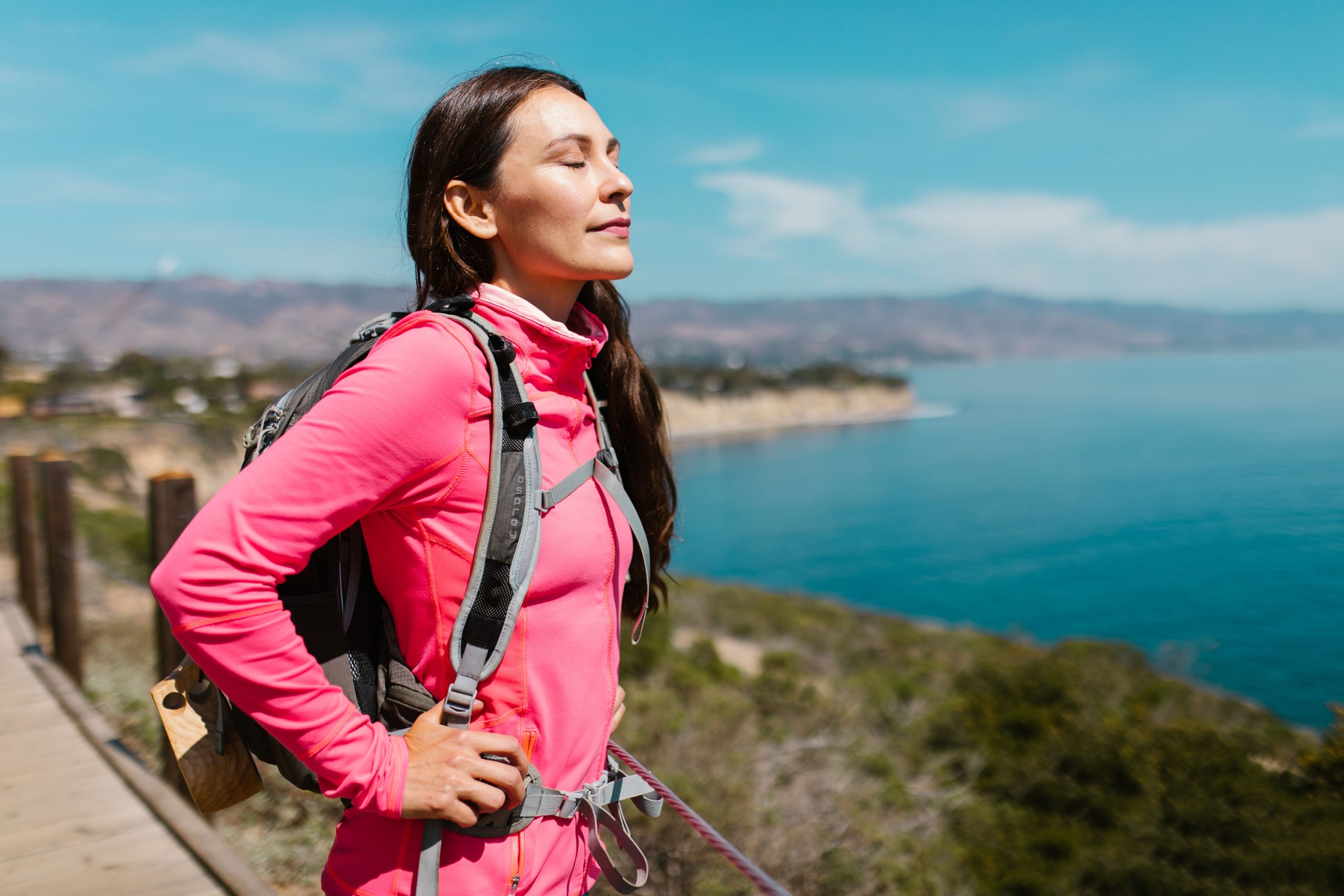 Femme en veste rose lors d'une randonnée côtière sereine