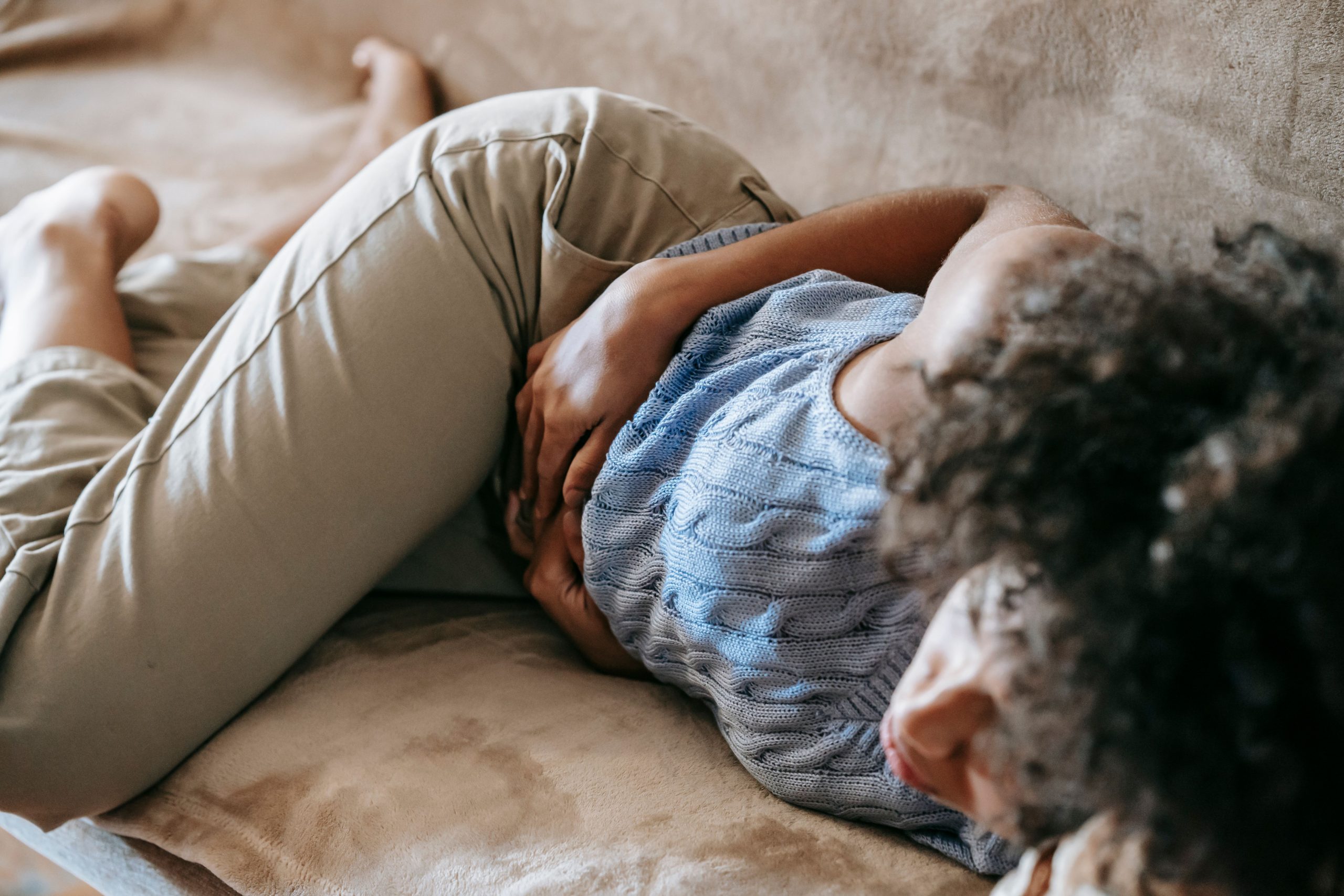 Femme allongée sur canapé souffrant douleur abdominale