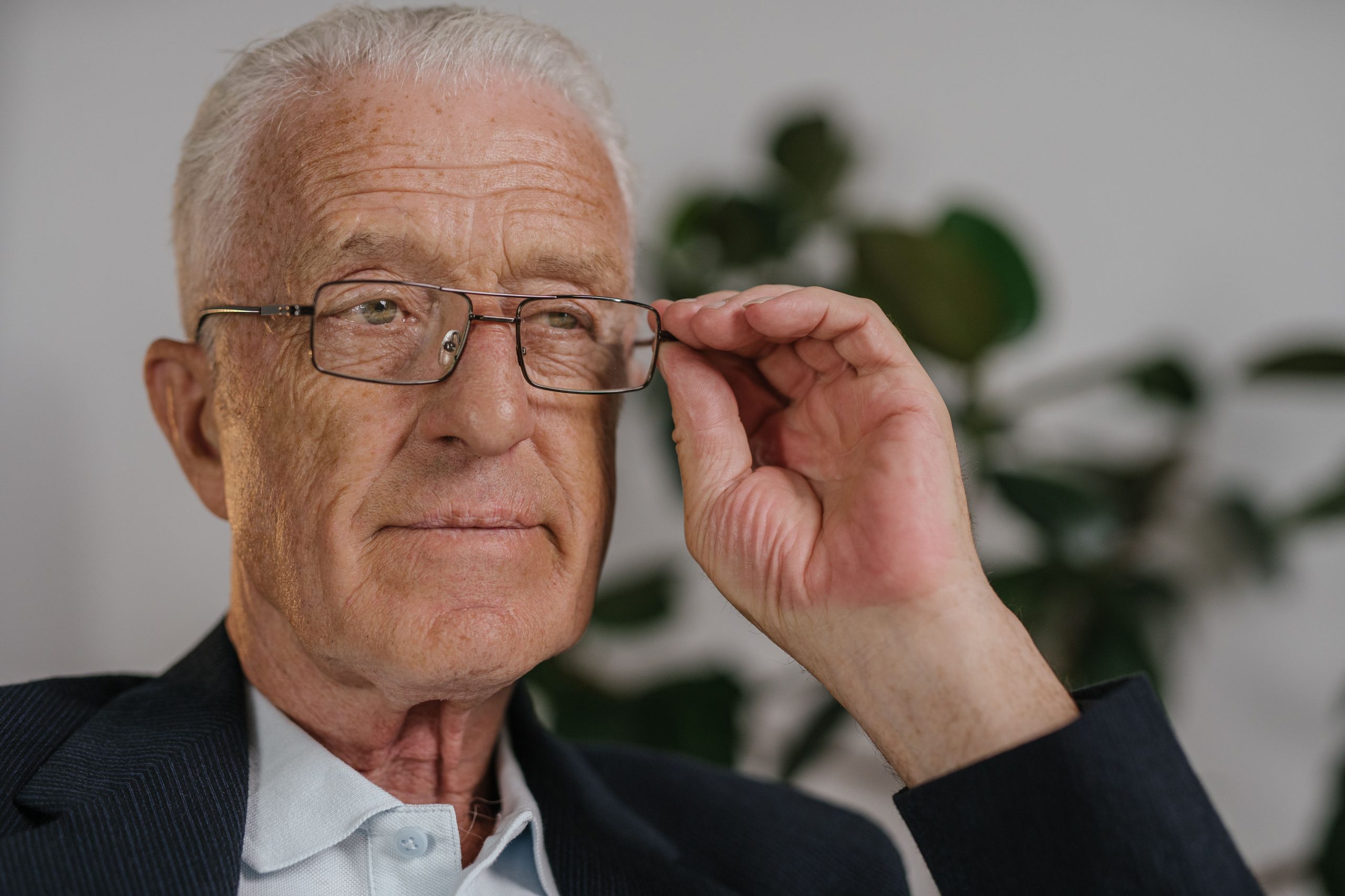 Homme âgé ajustant ses lunettes pensif