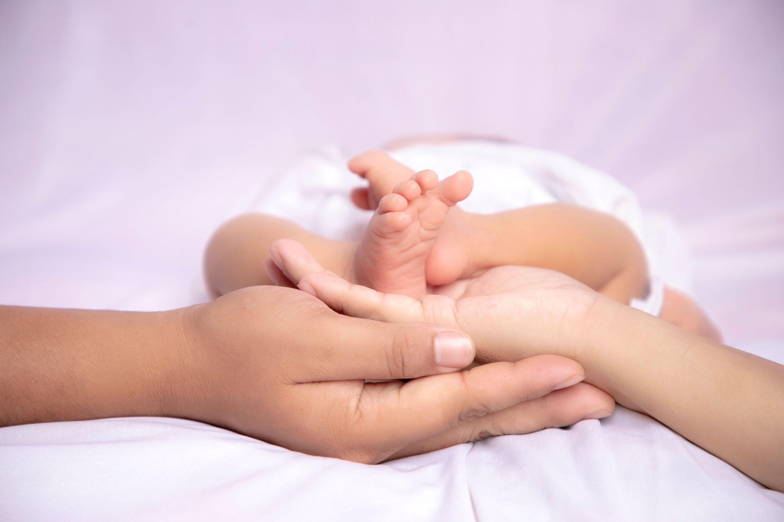 Mains des parents entourant les pieds du bébé