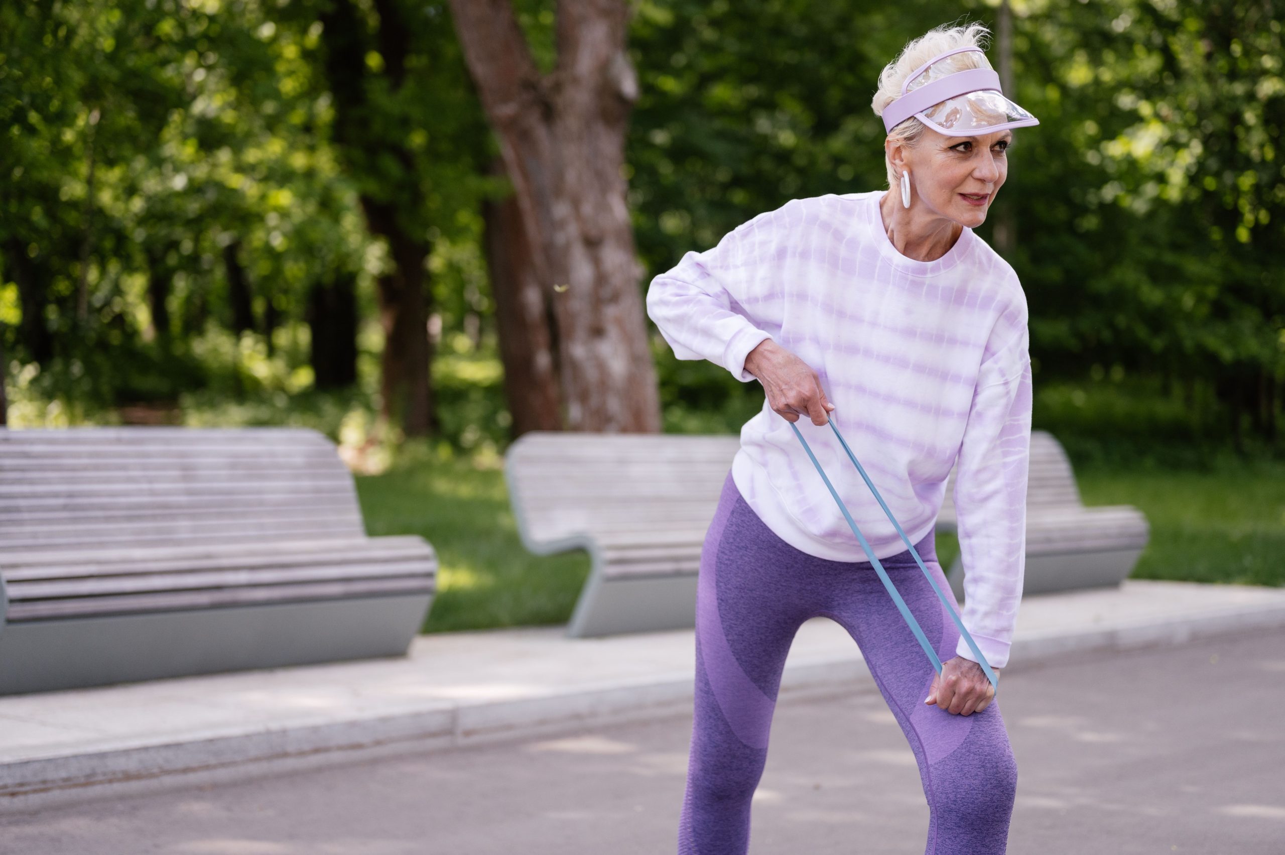 Femme senior exerce avec bande elastique dehors