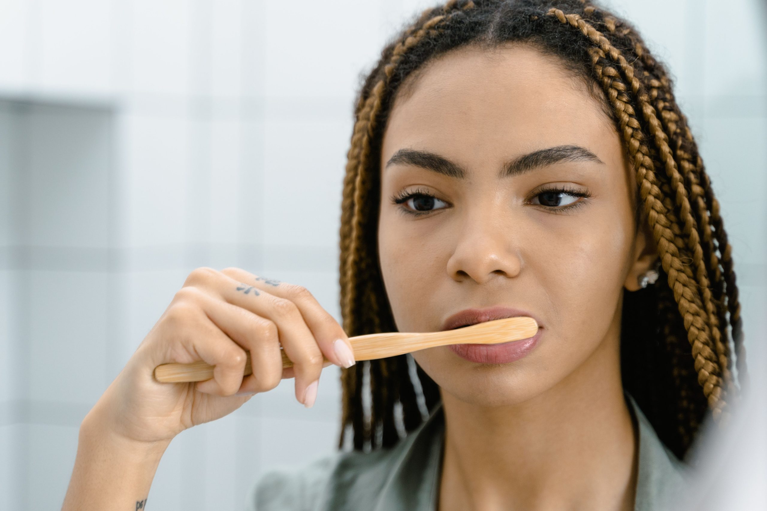 Femme aux cheveux tressés se brossant les dents