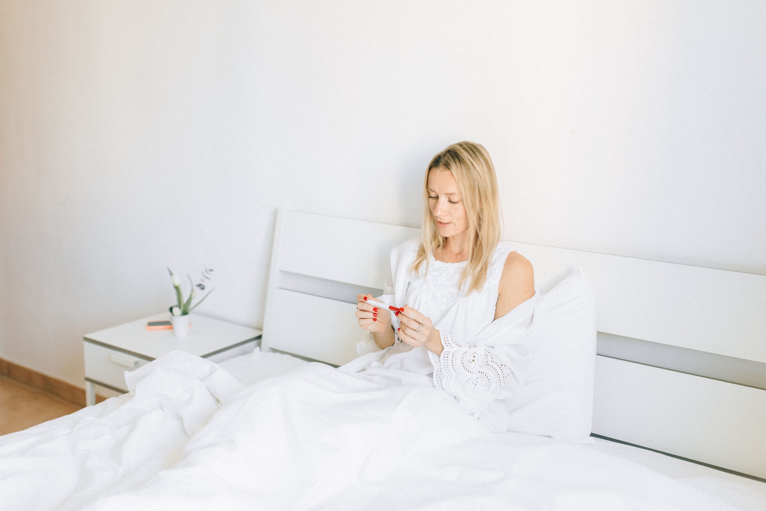 Femme au lit examinant un test de grossesse