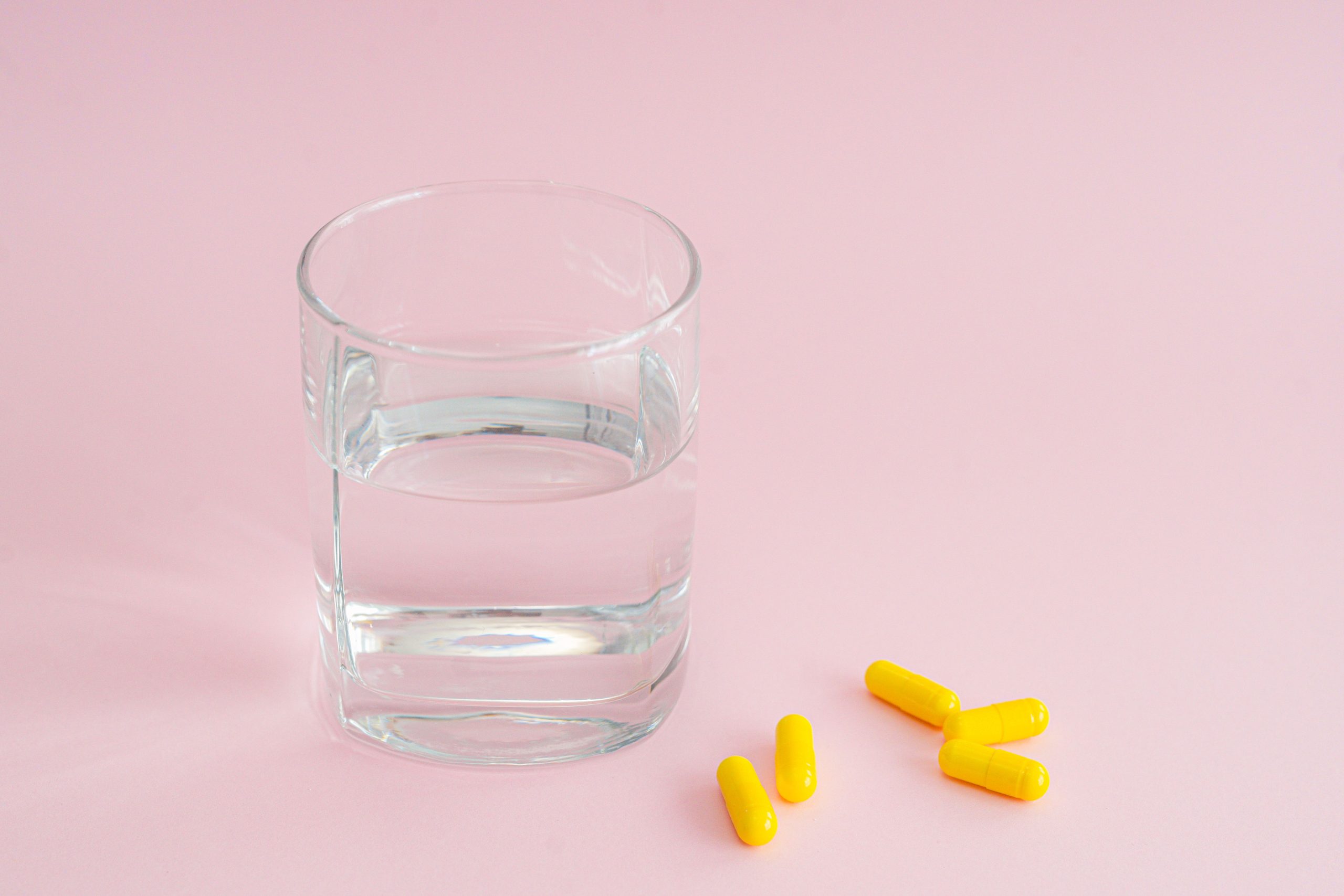 Verre d'eau et capsules jaunes santé bien-être